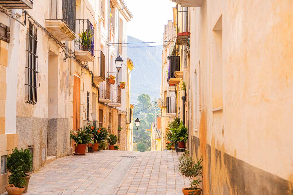 Cobbled street adorned with plants with mountains in the distance, Alicante