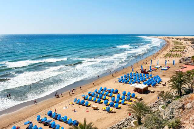 View of blue umbrellas on sandy beach, Playa del Ingles, Gran Canaria