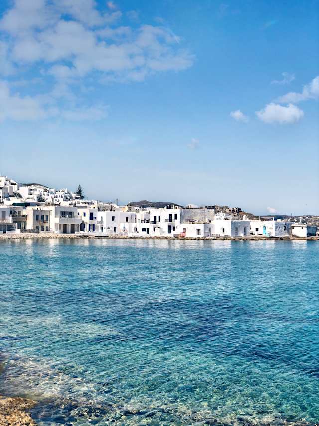 Clear blue water in a port town in front of white buildings in Paros, Greece