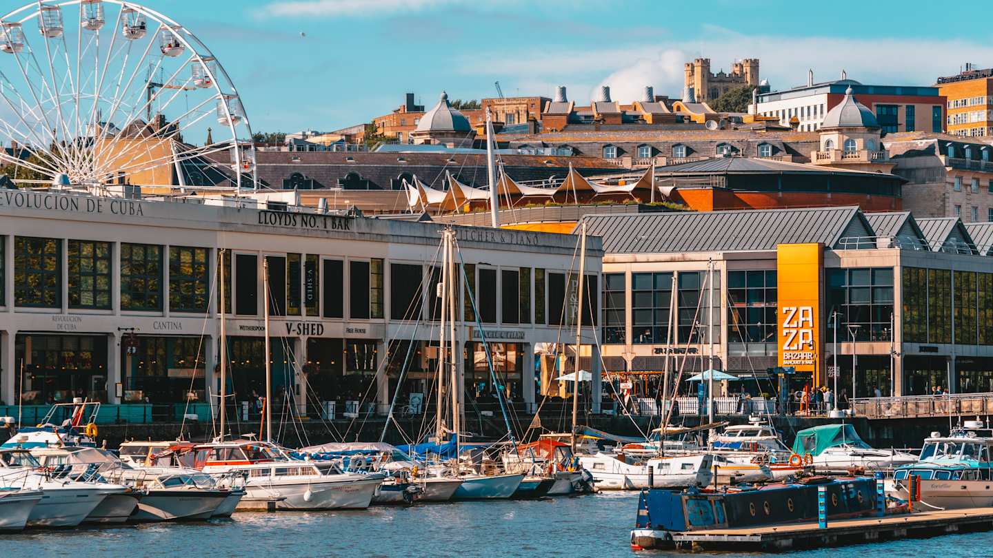 Boats in the water by buildings and a ferris wheel at Bristol Harbourside, England, UK