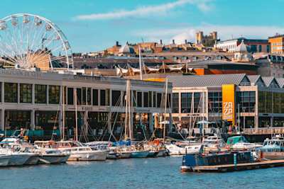 Boats in the water by buildings and a ferris wheel at Bristol Harbourside, England, UK