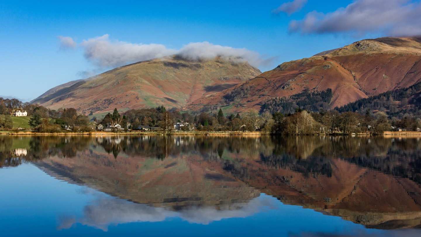 Large hills reflecting in a clear lake on a sunny day in Grasmere, Lake District, England, UK