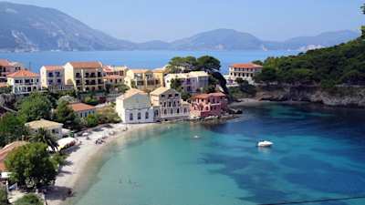 An aerial view of homes at a beach in front of distant mountains, Kefalonia, Greece