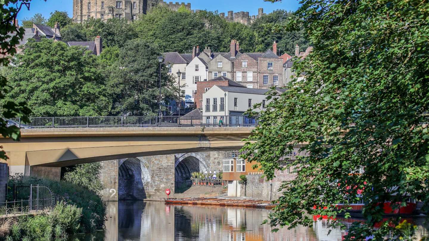 Durham Castle in the distance, behind trees and a lake, Durham, England, UK