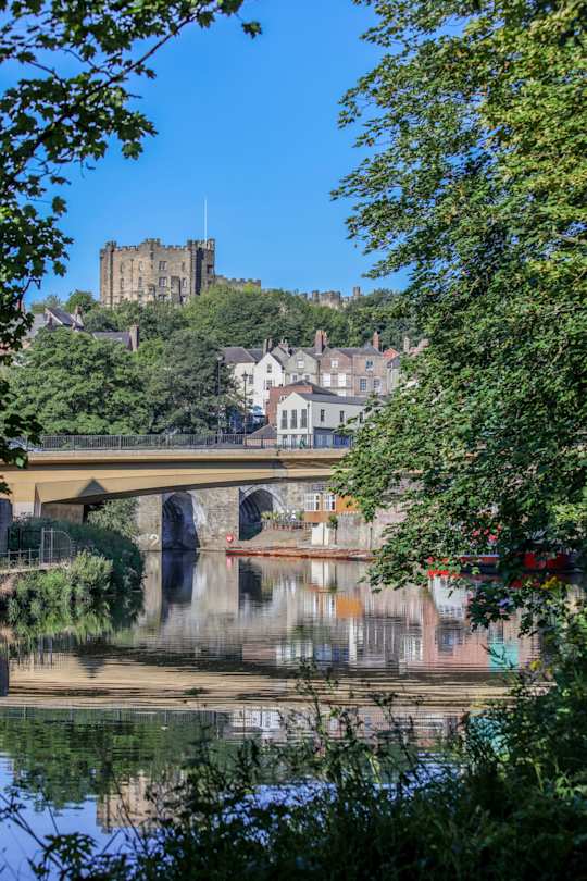 Durham Castle in the distance, behind trees and a lake, Durham, England, UK