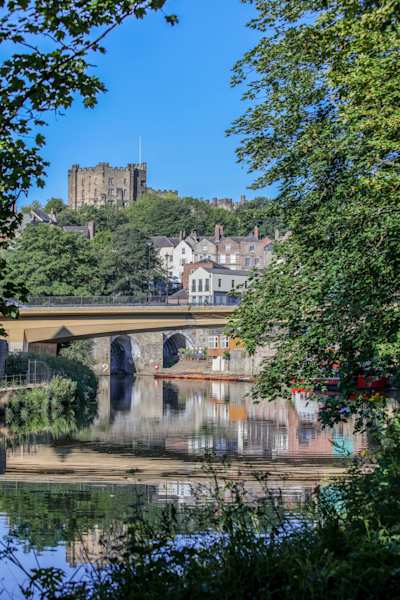 Durham Castle in the distance, behind trees and a lake, Durham, England, UK