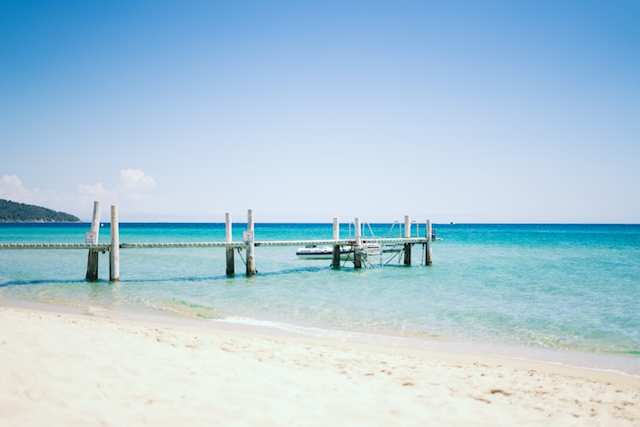 Wooden dock leading from sandy beach into the turquoise waters at Pampelonne Beach, Saint-Tropez