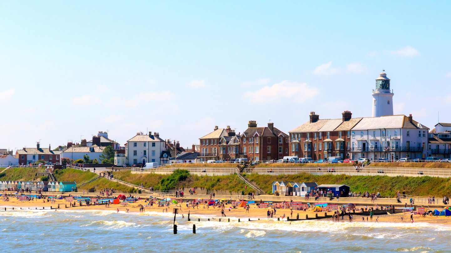 Seaside cottages, lighthouse, and beachgoers at Southwold Beach, Suffolk