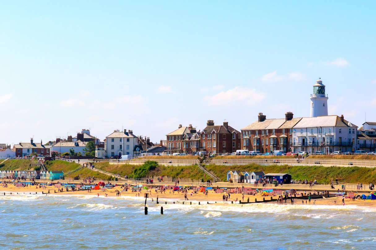 Seaside cottages, lighthouse, and beachgoers at Southwold Beach, Suffolk