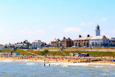 Seaside cottages, lighthouse, and beachgoers at Southwold Beach, Suffolk