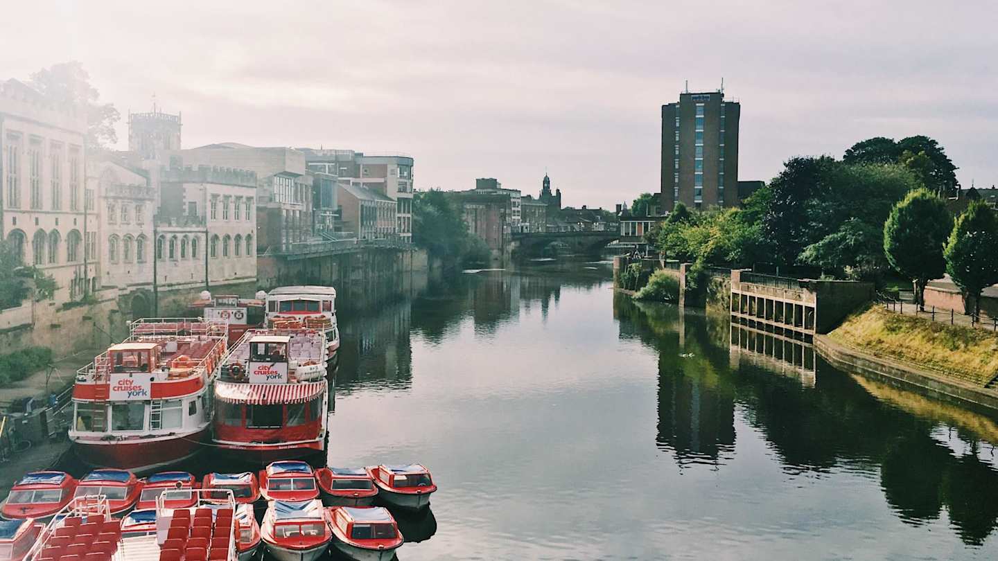 Small boats docked on the River Ouse city on a sunny day, York, England, UK