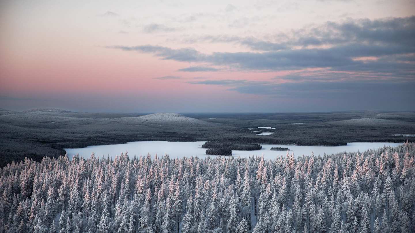 View of snow-covered trees and an icy lake from high up in Lapland, Finland