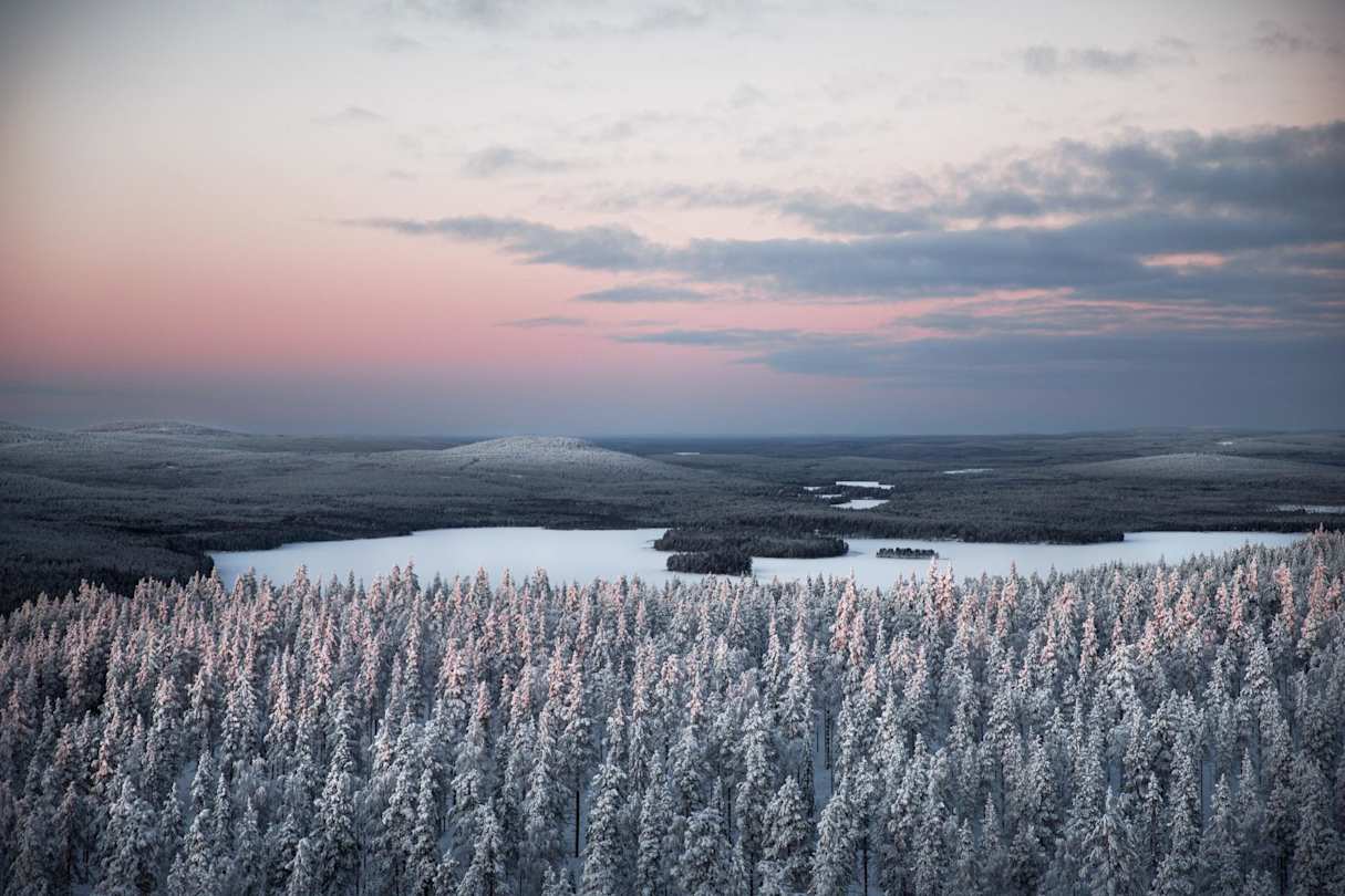 View of snow-covered trees and an icy lake from high up in Lapland, Finland