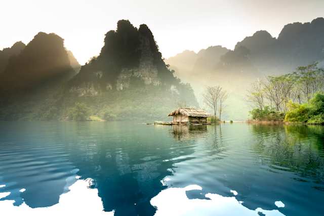 A small hut in the middle of a large lake by tall hills, Vietnam