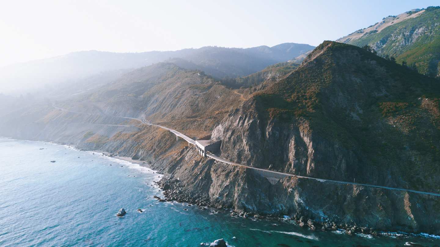 A large mountain next to a body of blue water at the Big Sur coastline, California