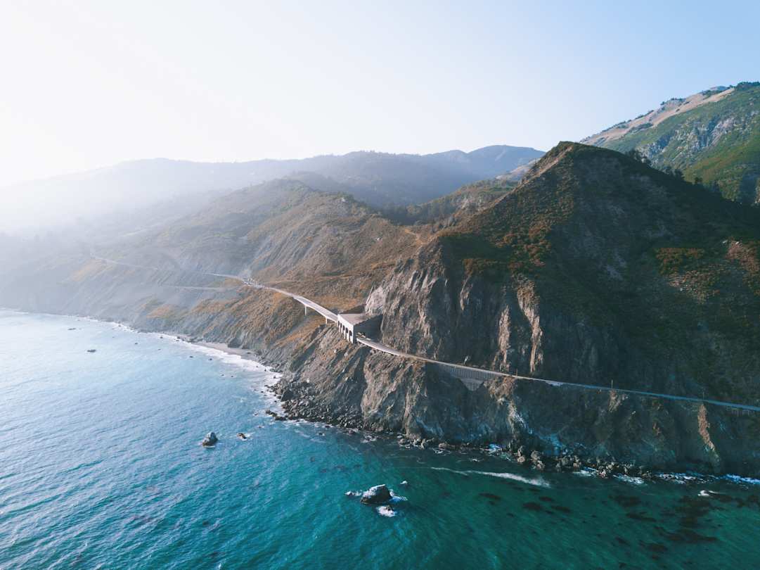 A large mountain next to a body of blue water at the Big Sur coastline, California