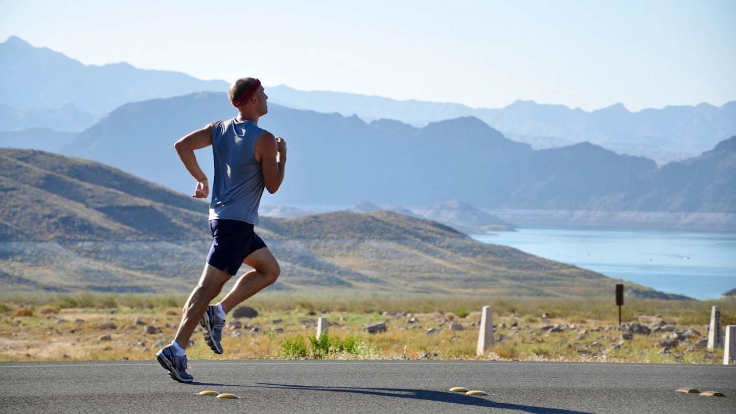man running with valley and hills and water in background