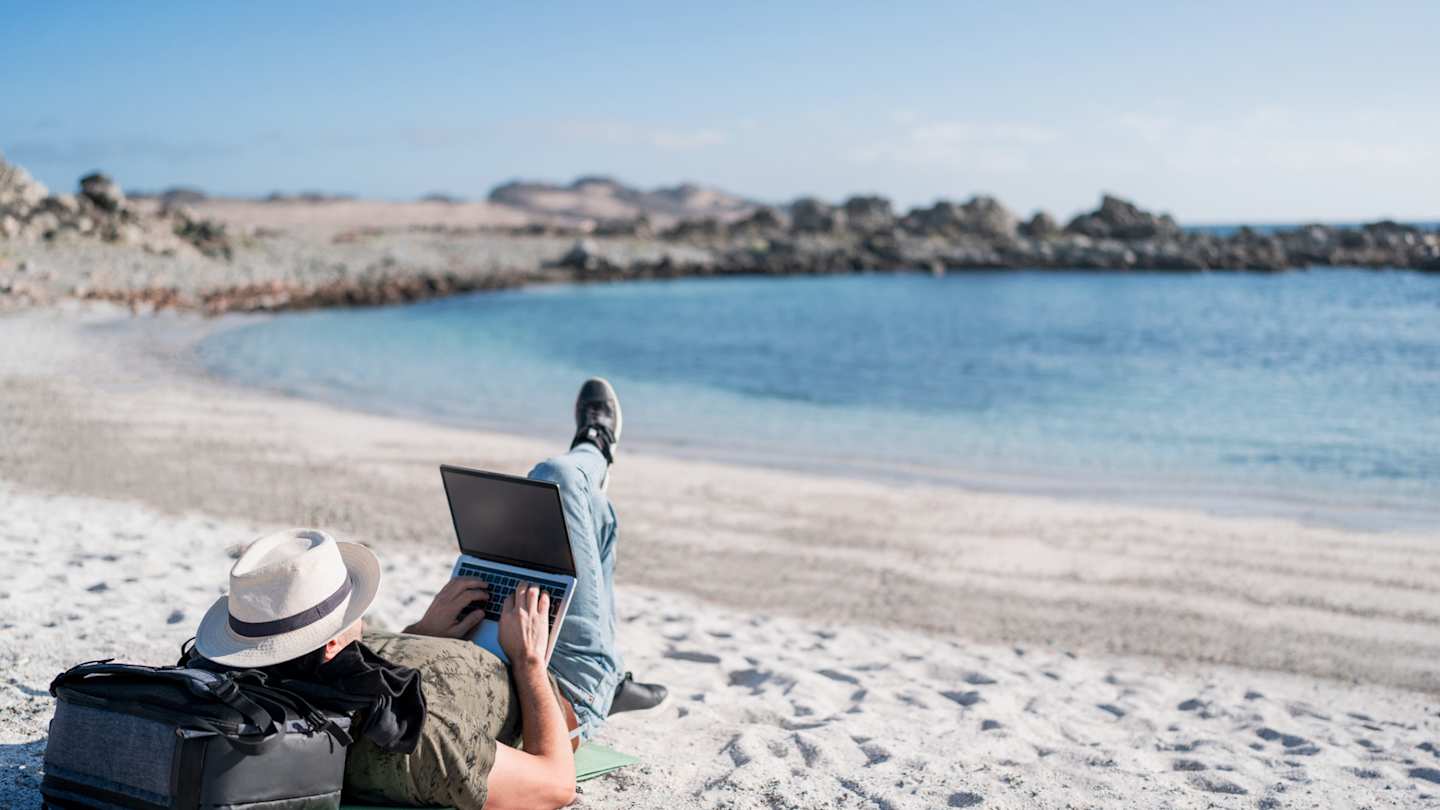 A digital nomad working from his laptop on the beach