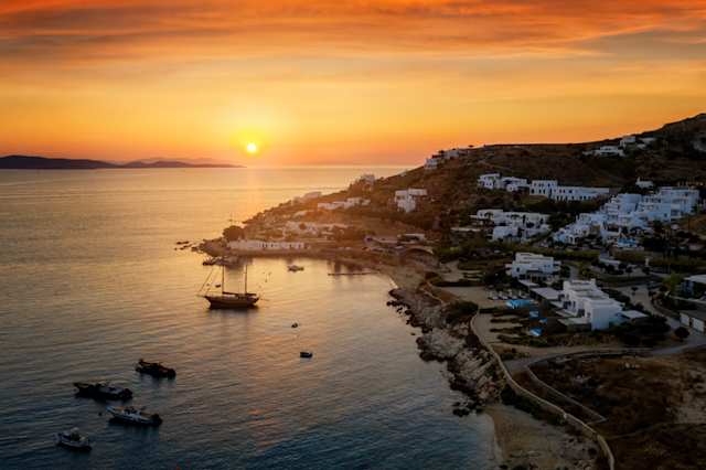 An aerial view of a sunset over houses and boats in Agios Ioannis, Mykonos, Greece