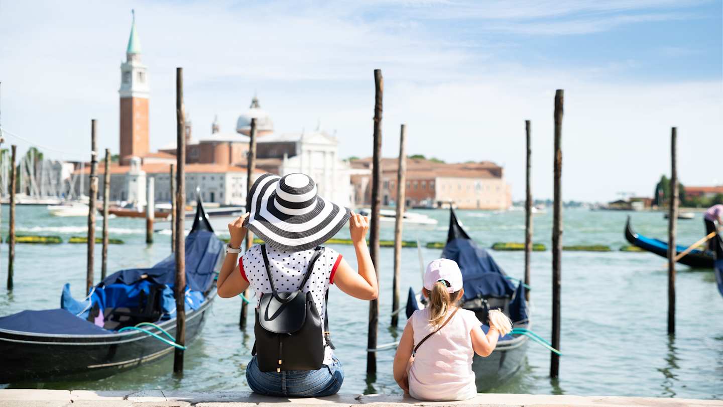 Mother and daughter sitting in front of gondolas looking at San Giorgio Maggiore, Venice, Italy