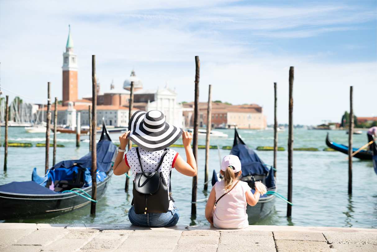 Mother and daughter sitting in front of gondolas looking at San Giorgio Maggiore, Venice, Italy