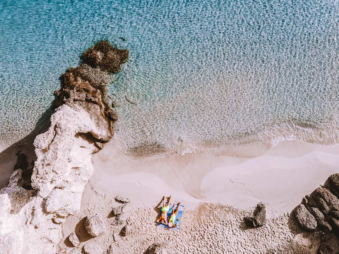 A bird's eye view of a couple sunbathing together on a pristine beach in Crete, Greece