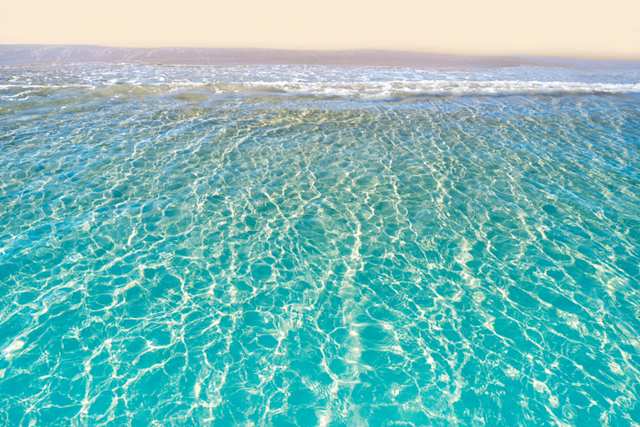 Pristine blue sea gently rolling onto a sandy beach in summer, Tarragona, Spain