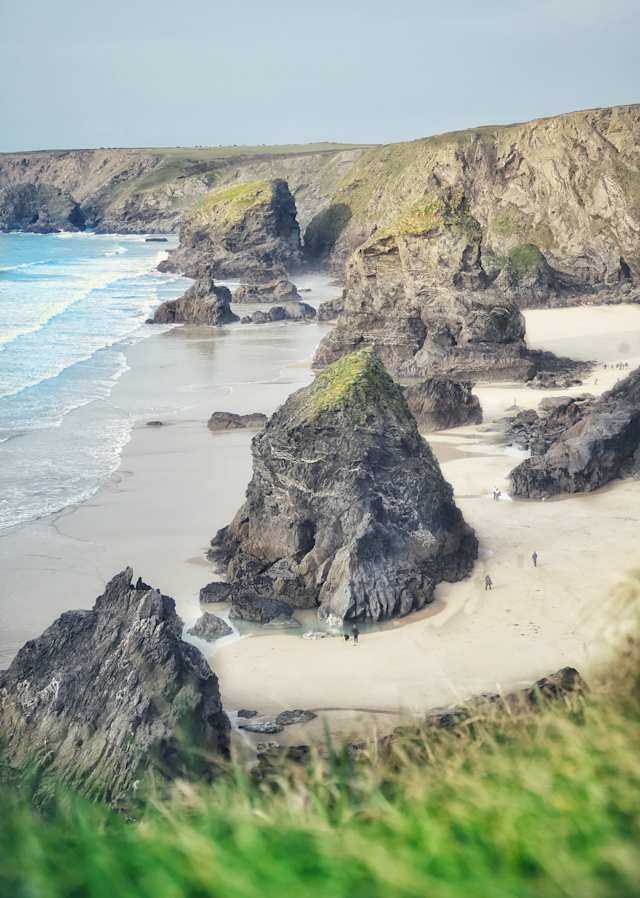 People exploring the large rock formations at Bedruthan Steps on the sand at the beach, Cornwall, England, UK