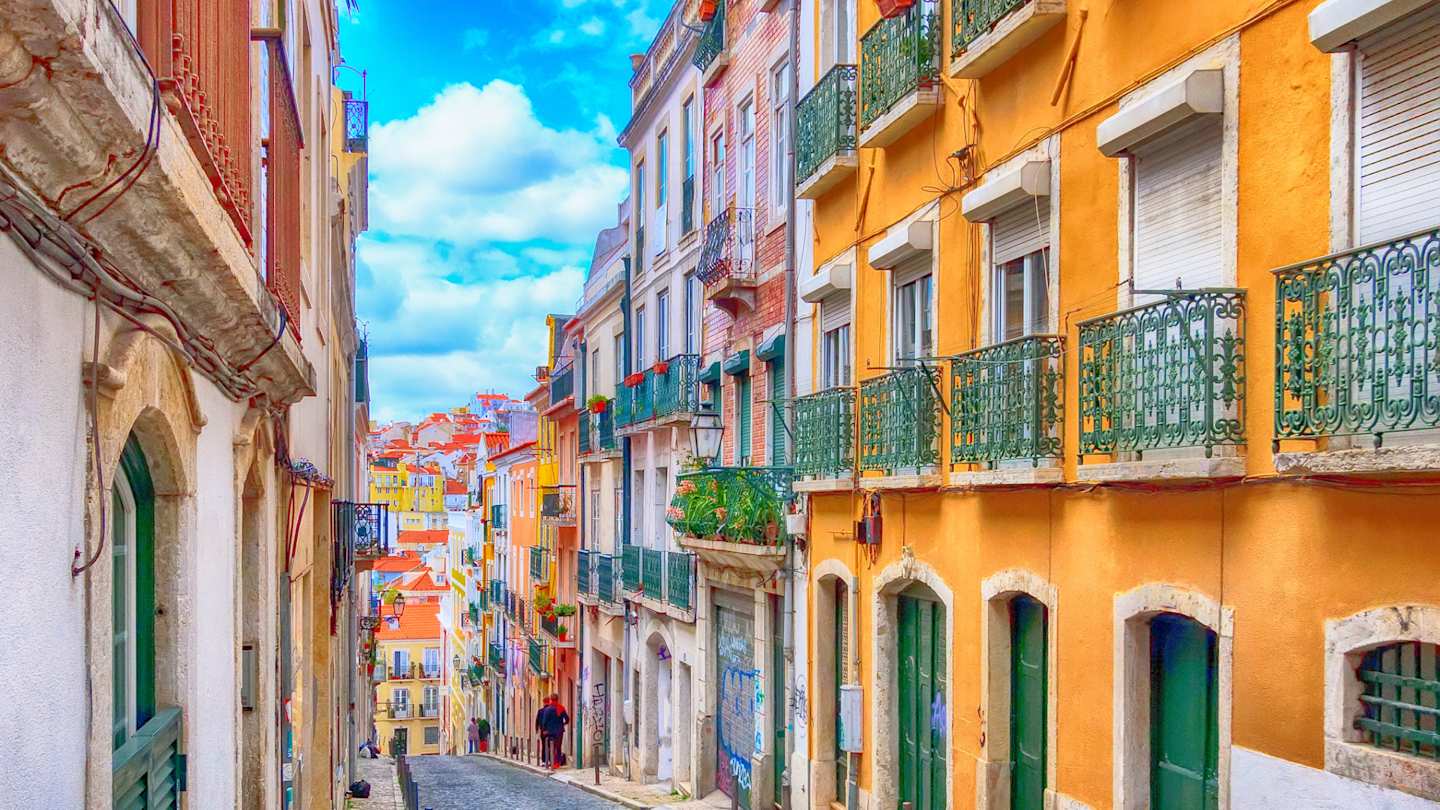 A cobblestone street with colourful traditional houses in Lisbon, Portugal