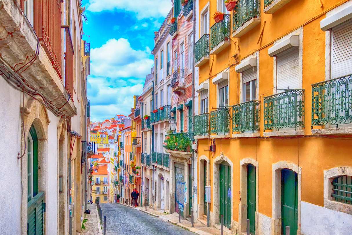 A cobblestone street with colourful traditional houses in Lisbon, Portugal
