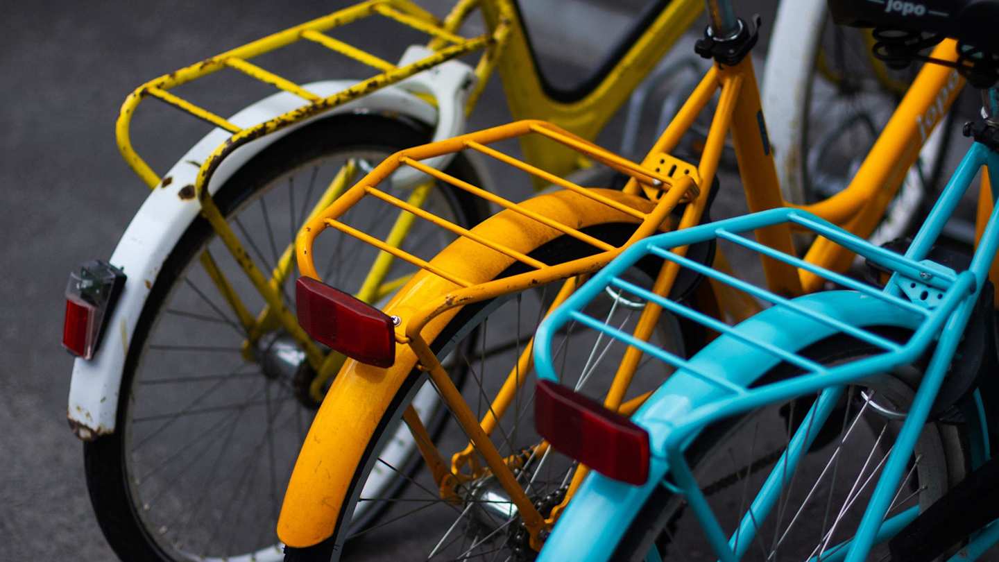 A close up view of three colourful bicycles in a bike rack