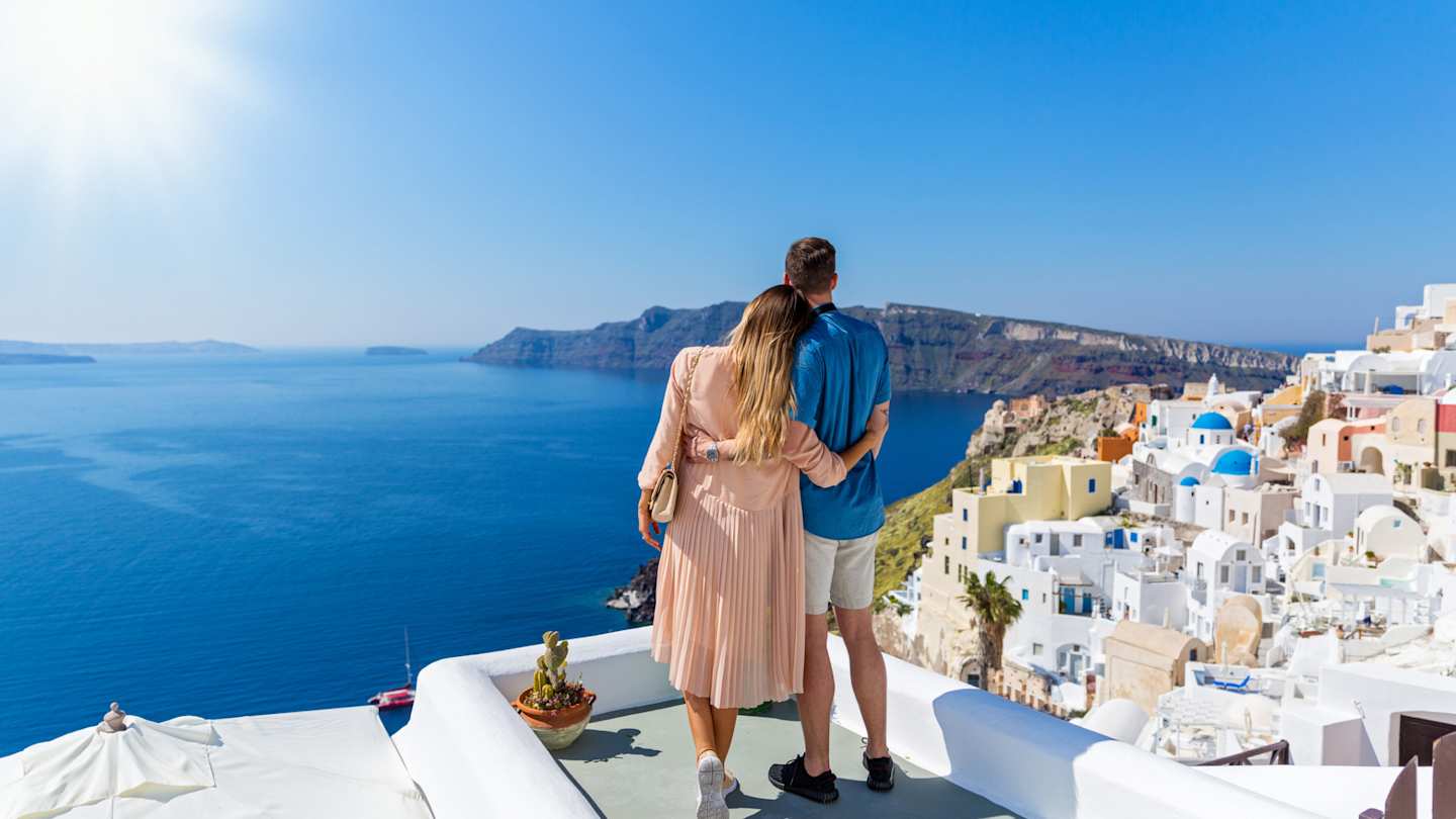 A young couple standing together looking out over the sea in Santorini, Greece