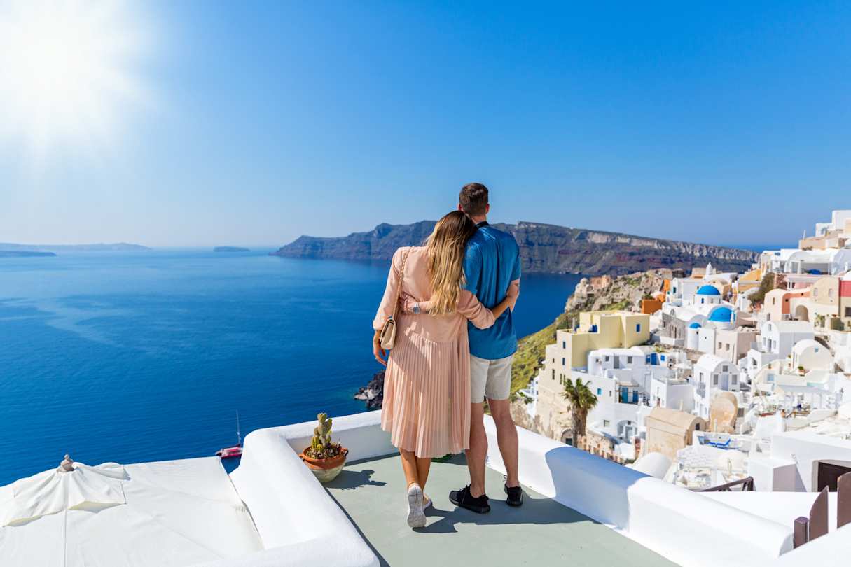 A young couple standing together looking out over the sea in Santorini, Greece