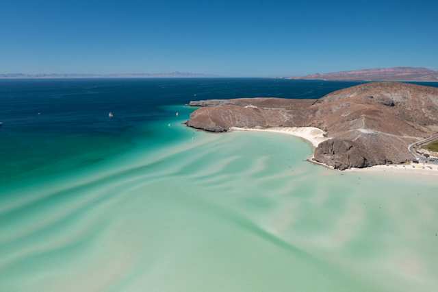 An aerial view of clear blue water and white sand at Balandra Beach, Baja California Sur, Mexico