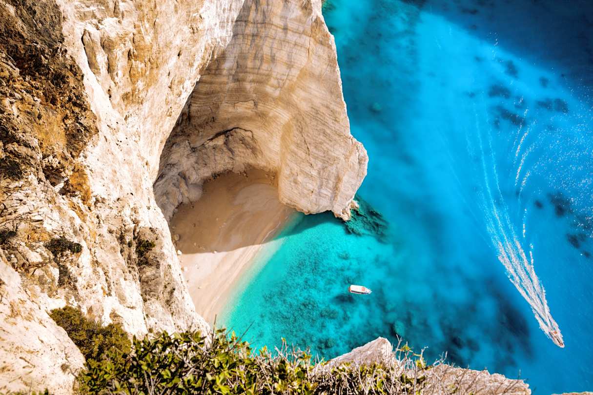 A bird's eye view of a white boat on the clear blue sea by a beach in Zakynthos, Greece