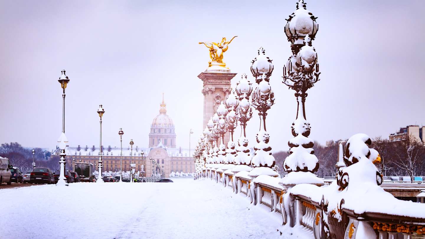 A close up of snow on the Pont Alexandre III bridge in front of a cathedral in Paris in winter, France