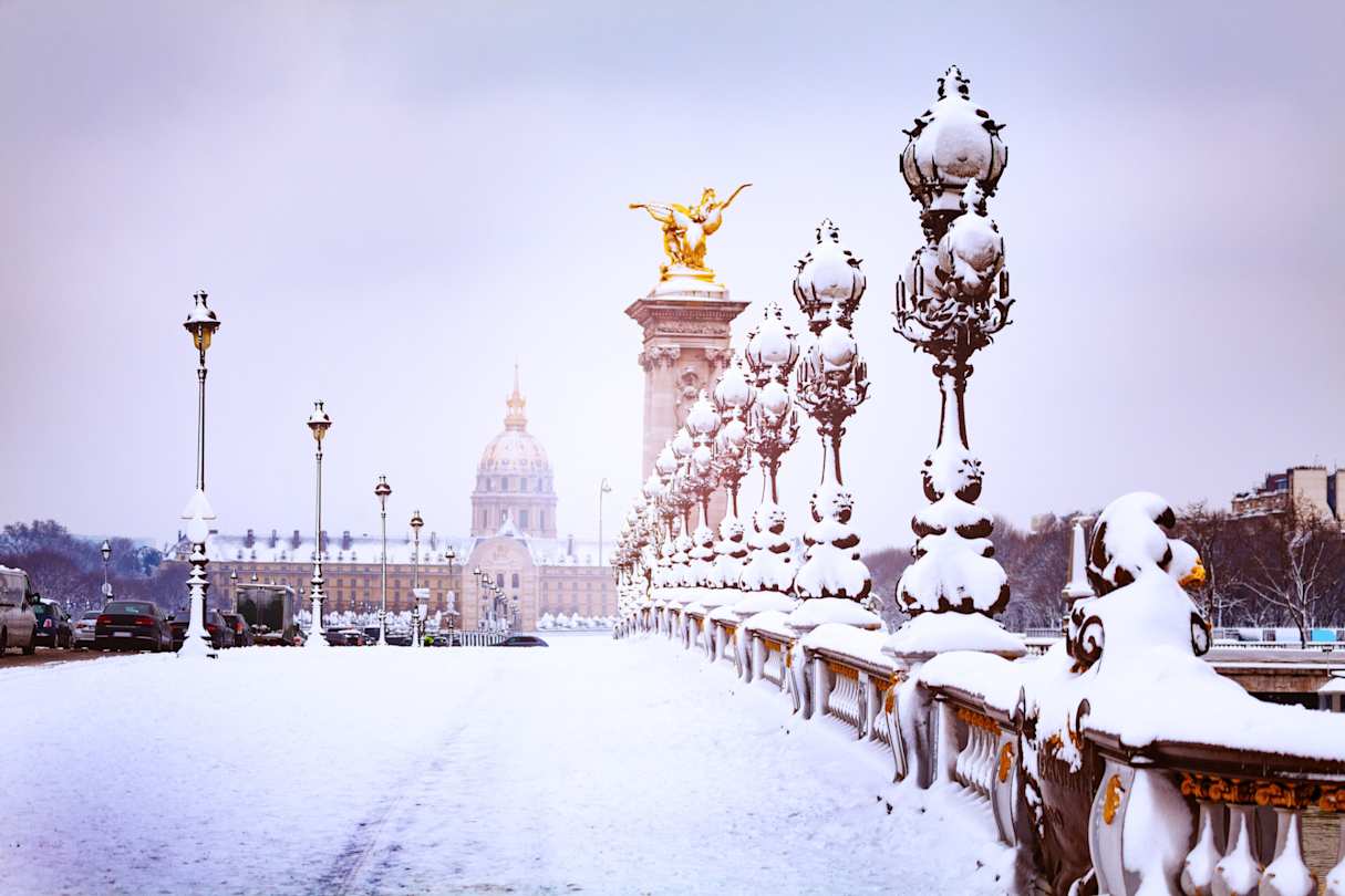 A close up of snow on the Pont Alexandre III bridge in front of a cathedral in Paris in winter, France