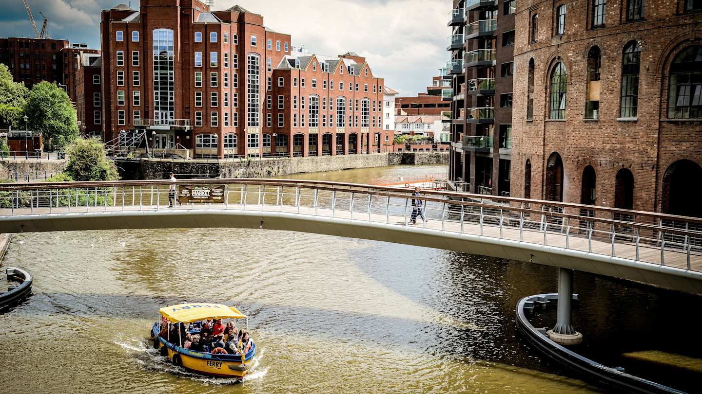 A boat sailing under a bridge at Bristol Harbour, UK