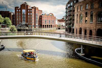 A boat sailing under a bridge at Bristol Harbour, UK