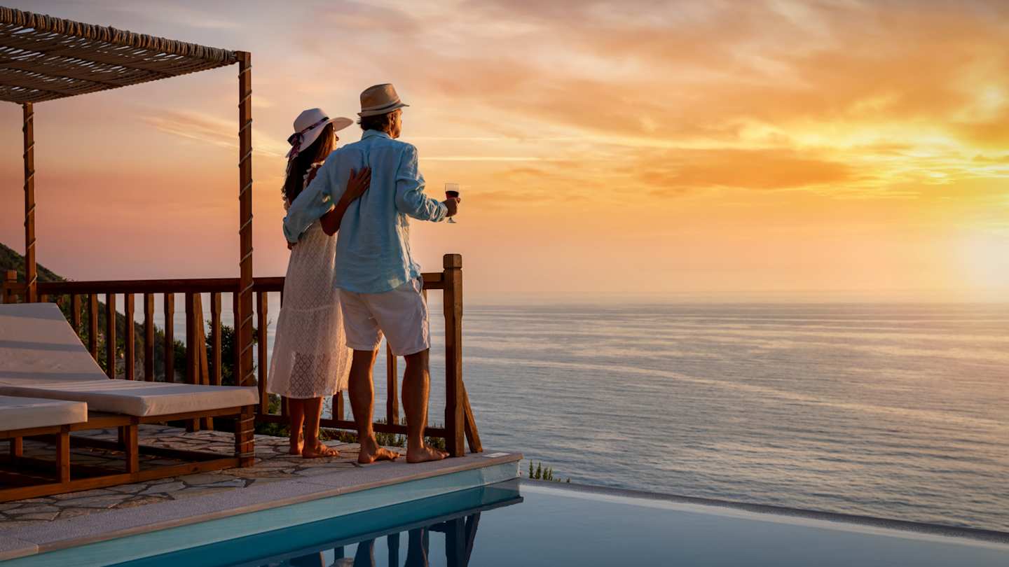 A couple looking out to sea from a private villa at sunset
