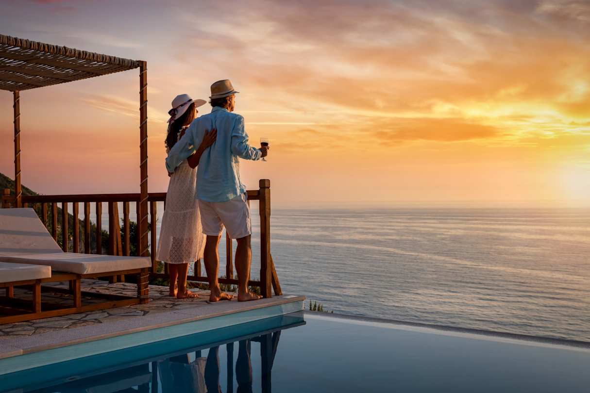 A couple looking out to sea from a private villa at sunset