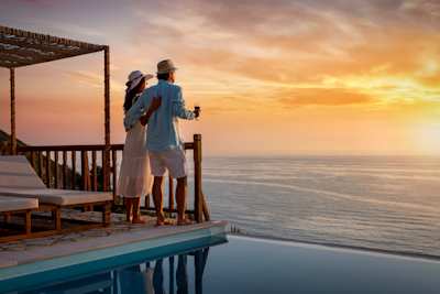 A couple looking out to sea from a private villa at sunset