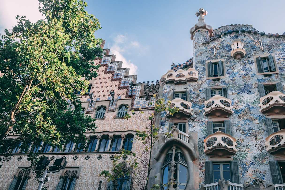 The Gaudí masterpiece Casa Batlló and a tiled building on a tree-lined street in Barcelona, Spain