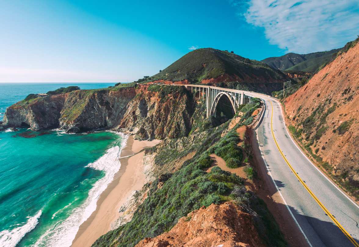 The Pacific Coast Highway, alongside the bright blue sea and tall hills, California, US