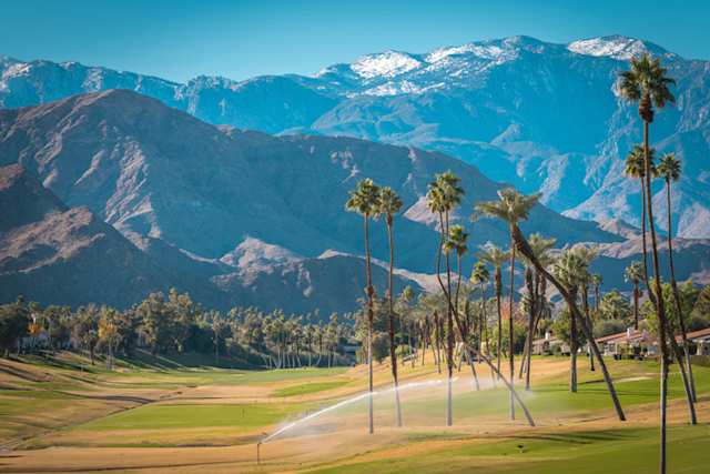 Scenic view of mountains, golf course, and palm trees in Palm Desert, near Palm Springs, California