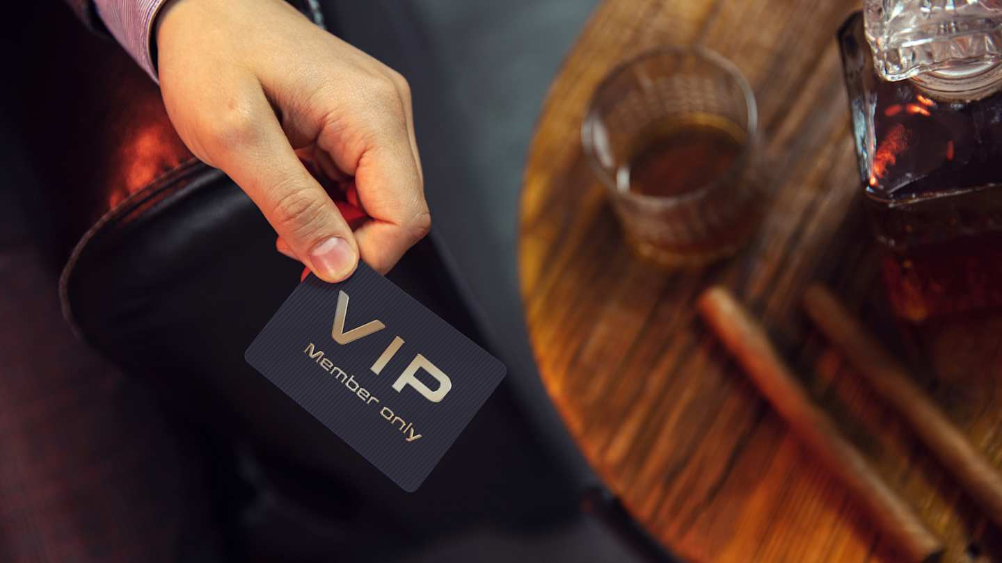 A person holding a VIP member's club card by some cigars at a bar