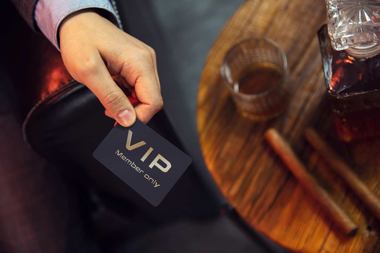 A person holding a VIP member's club card by some cigars at a bar
