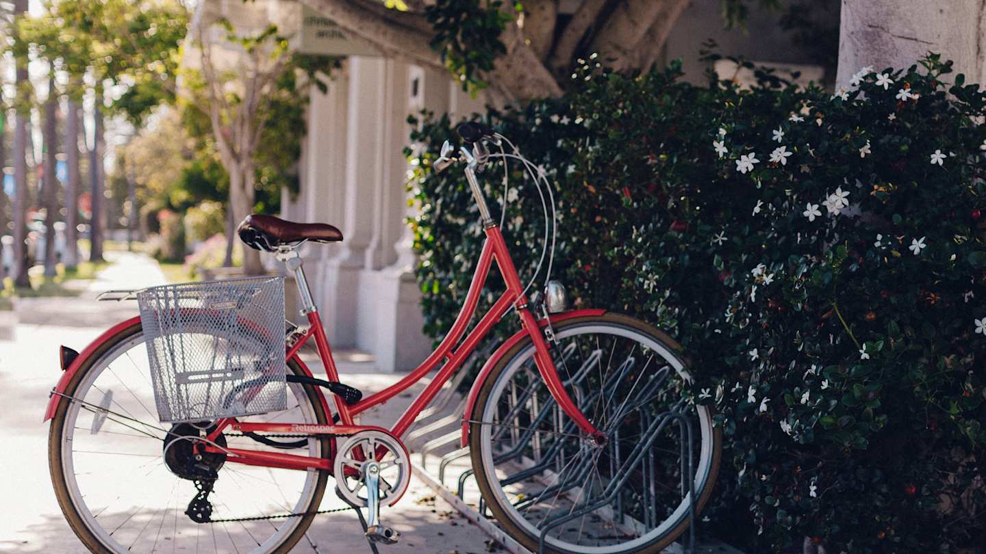 A red bicycle at a bike stand on the pavement