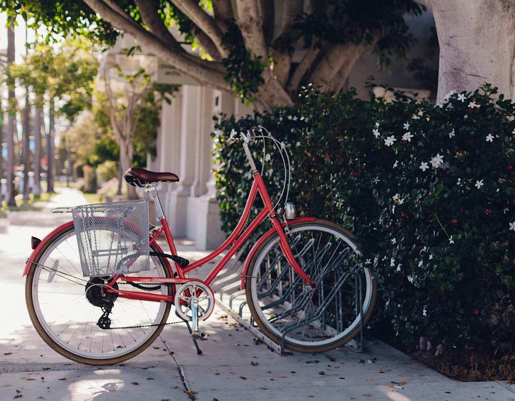 A red bicycle at a bike stand on the pavement