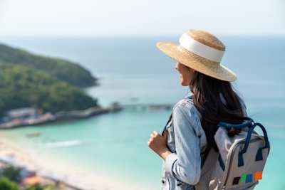 A young woman smiling as she walks near a sandy beach on holiday